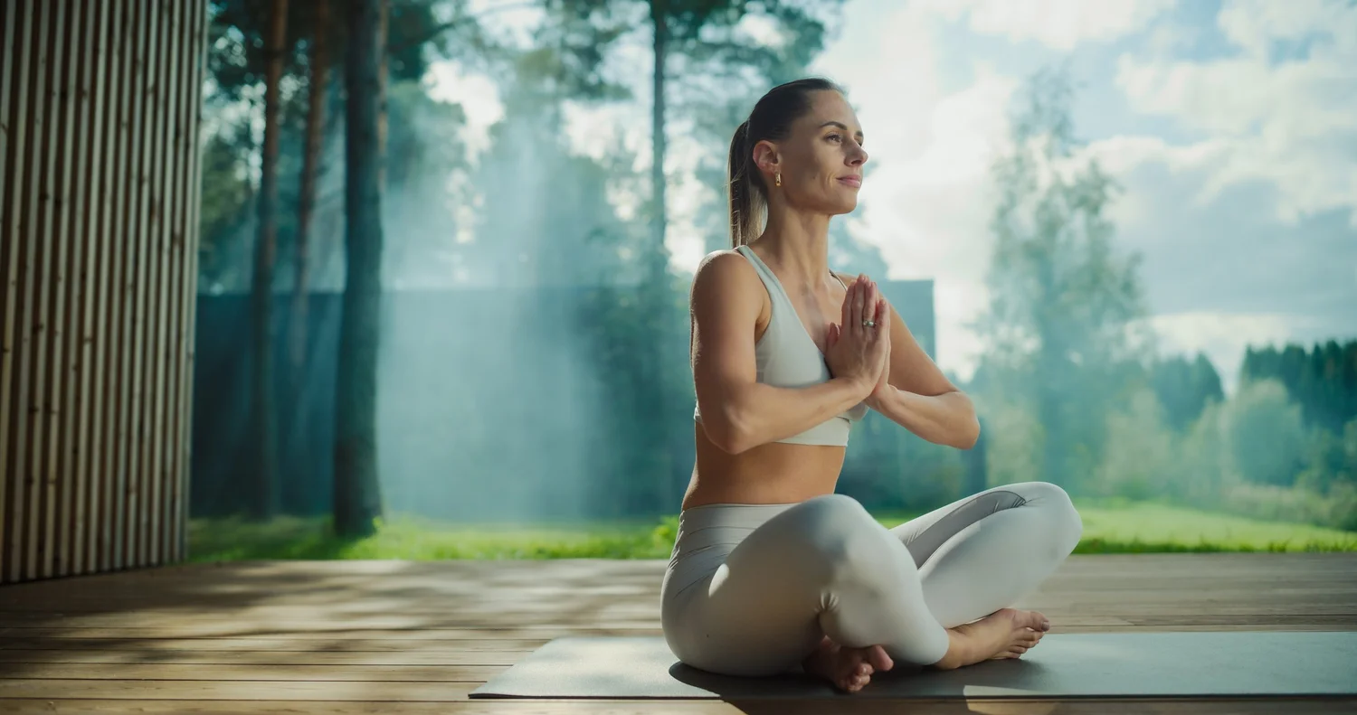 A person seated in stillness beside water, eyes closed
