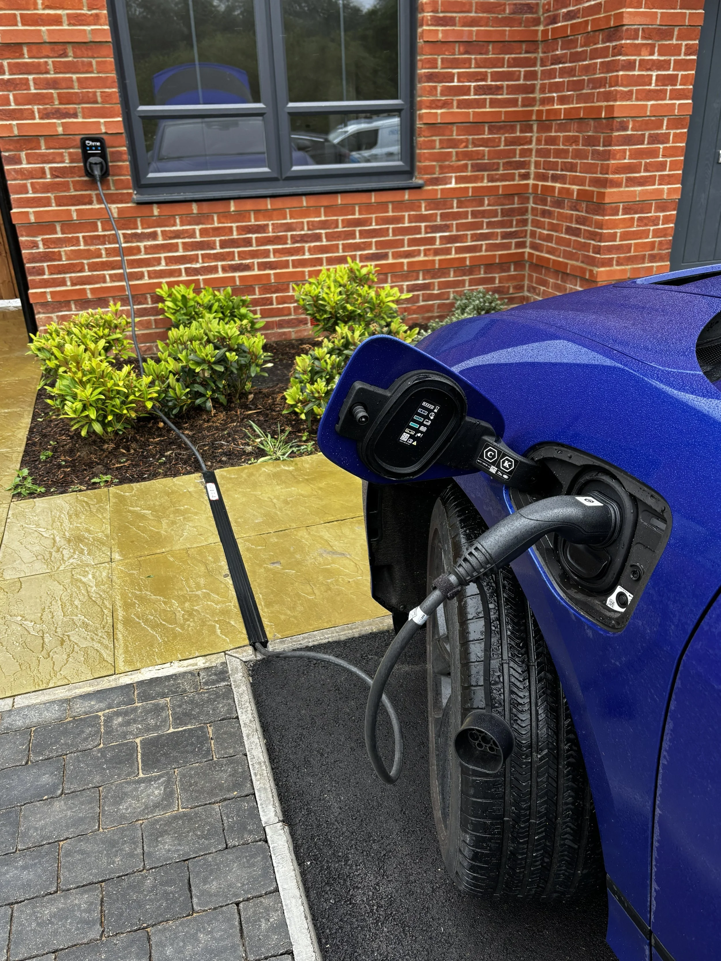 Resident charging an EV over a Kerbo Charge channel outside a new build home