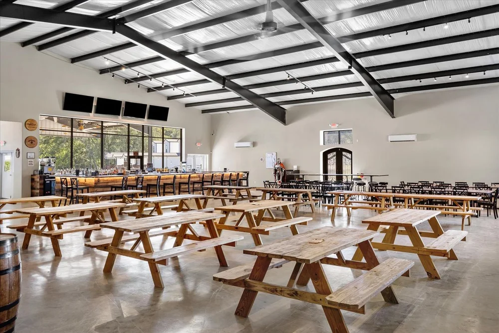 Open event hall with picnic tables and TVs