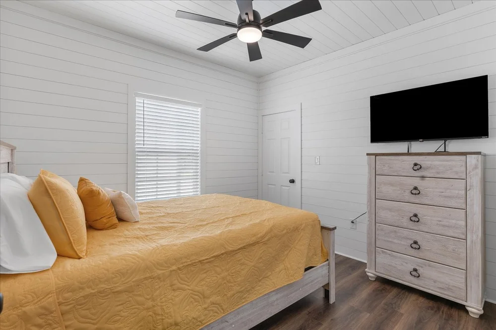 Cabin bedroom with ceiling fan and dresser