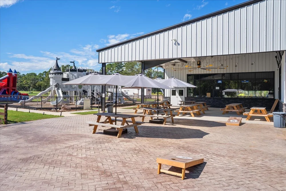 Patio with picnic tables, umbrellas and cornhole boards