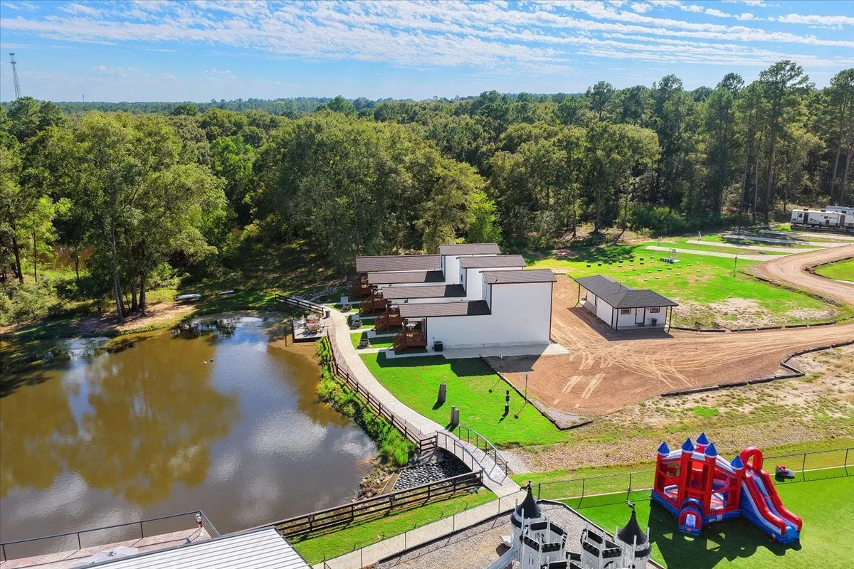 Aerial view of the guest cabins beside the pond, with the playground and RV sites beyond