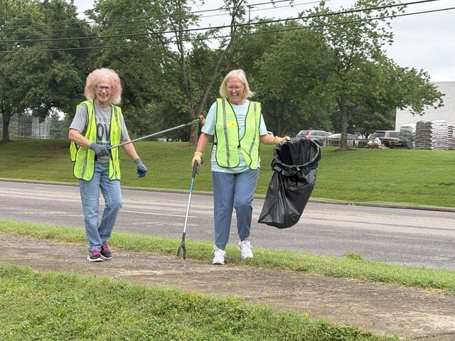 Two volunteers laughing while picking up litter