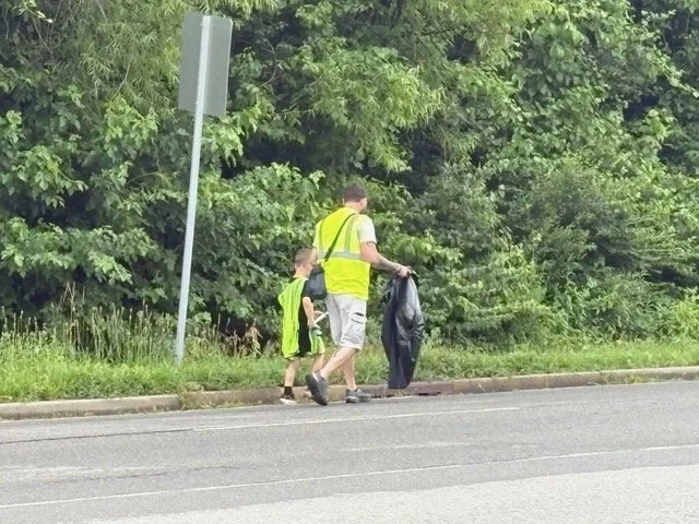 A dad and his son picking up trash along the road