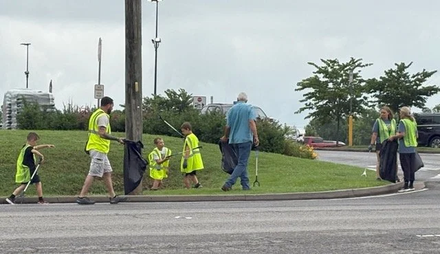 Kids and adults picking up litter along a curb
