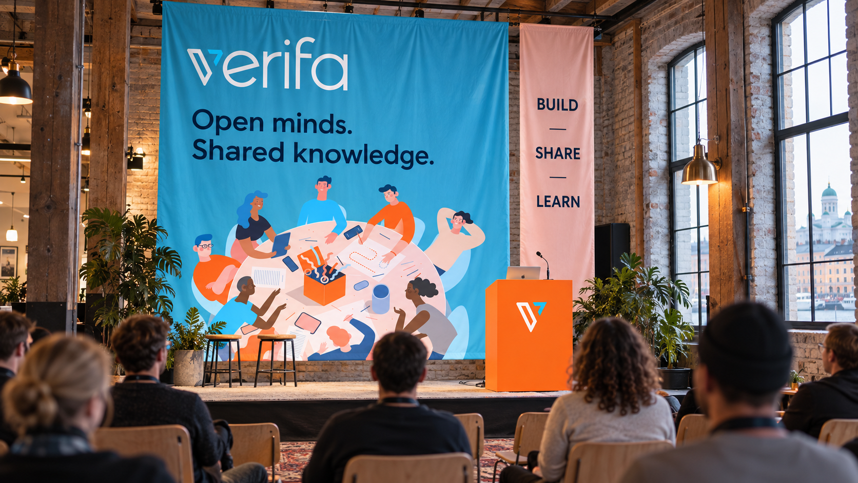 Verifa community meetup environment concept with cyan illustrated fabric banners, an orange lectern and a Helsinki workshop setting