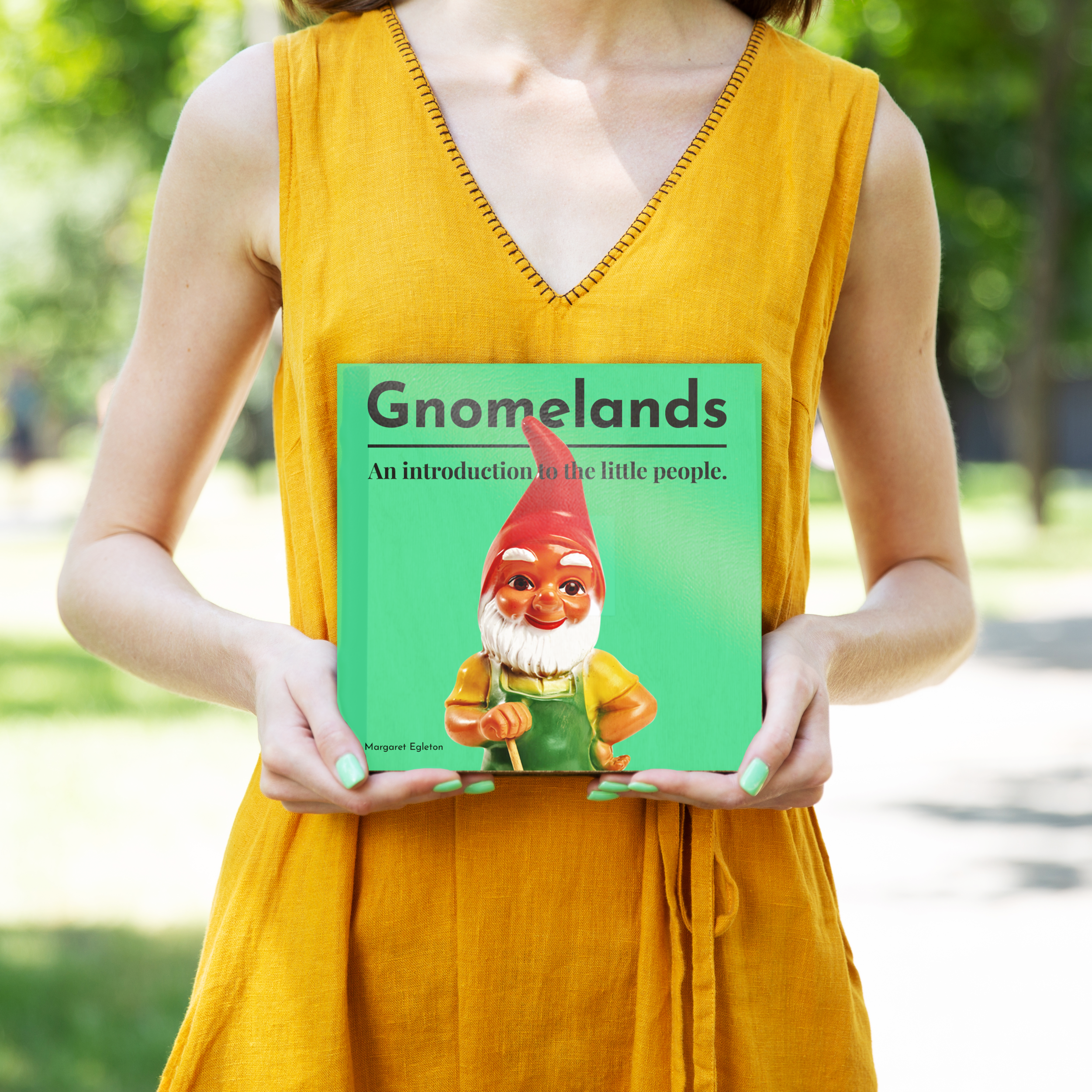 Original Gnomelands book-cover design held outdoors, with a red-hat gnome on a green cover