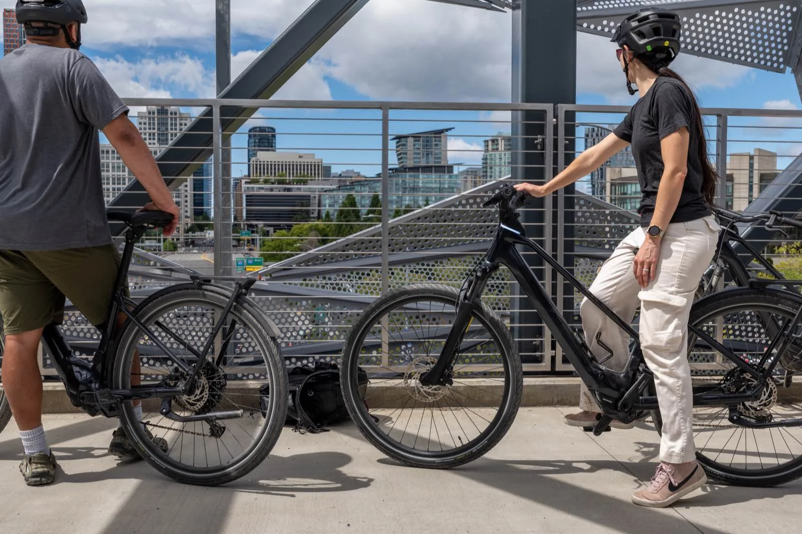 Two flat bar bikes held at the Eastrail overlook with the Bellevue skyline behind