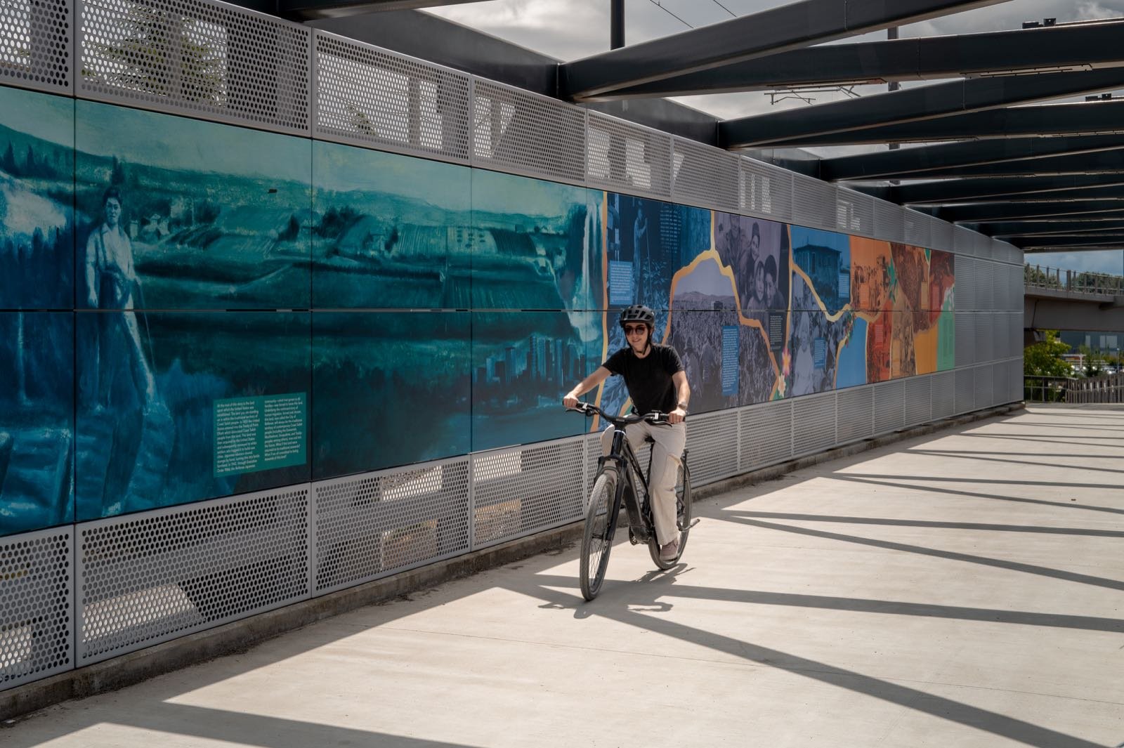 A rider crossing the NE 8th Street bridge beside the art and poetry installation