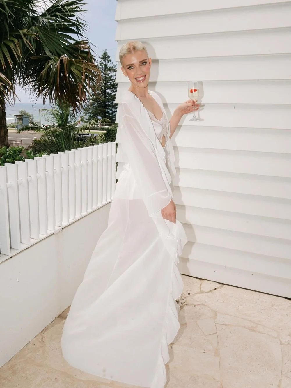 Bride in a sheer robe on a balcony by the beach