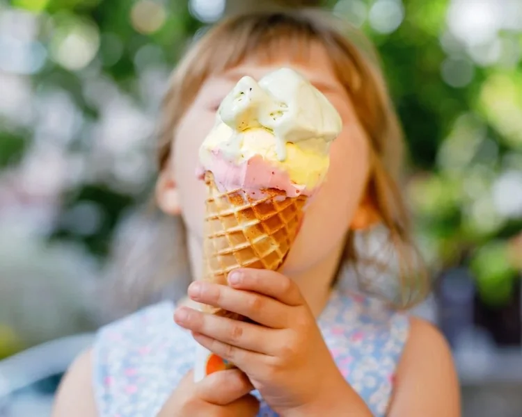 Girl eating ice cream in a waffle cone at Speculator Creamer.