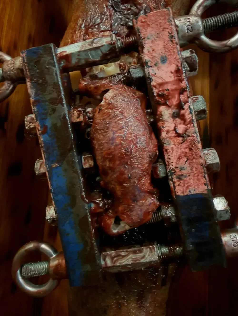 The knee crusher scene from Daddy's Little Girl: a bloodied knee clamped in a bolted steel rig, a practical effect by Steve Boyle.