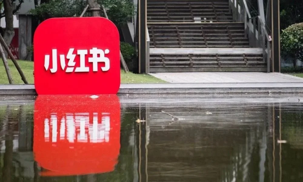 Little Red Book Xiaohongshu logo with miniature figures representing the community-driven social commerce model in China