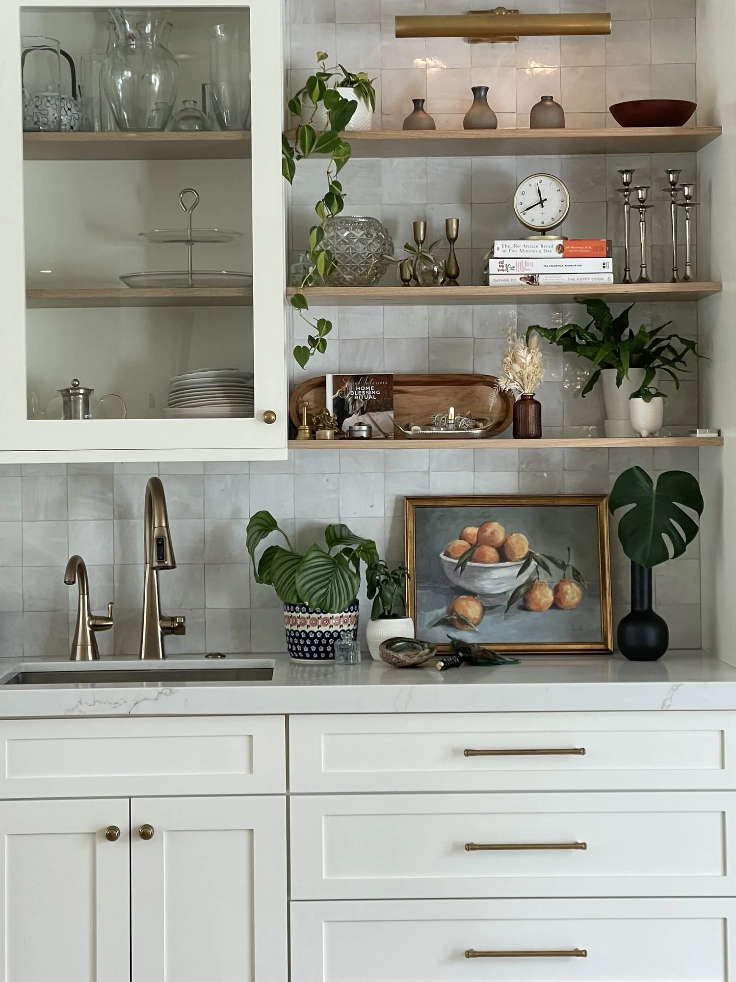 A styled corner with open shelving, art, glassware and plants