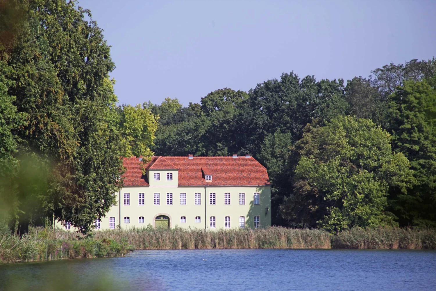 A historic waterside house surrounded by trees