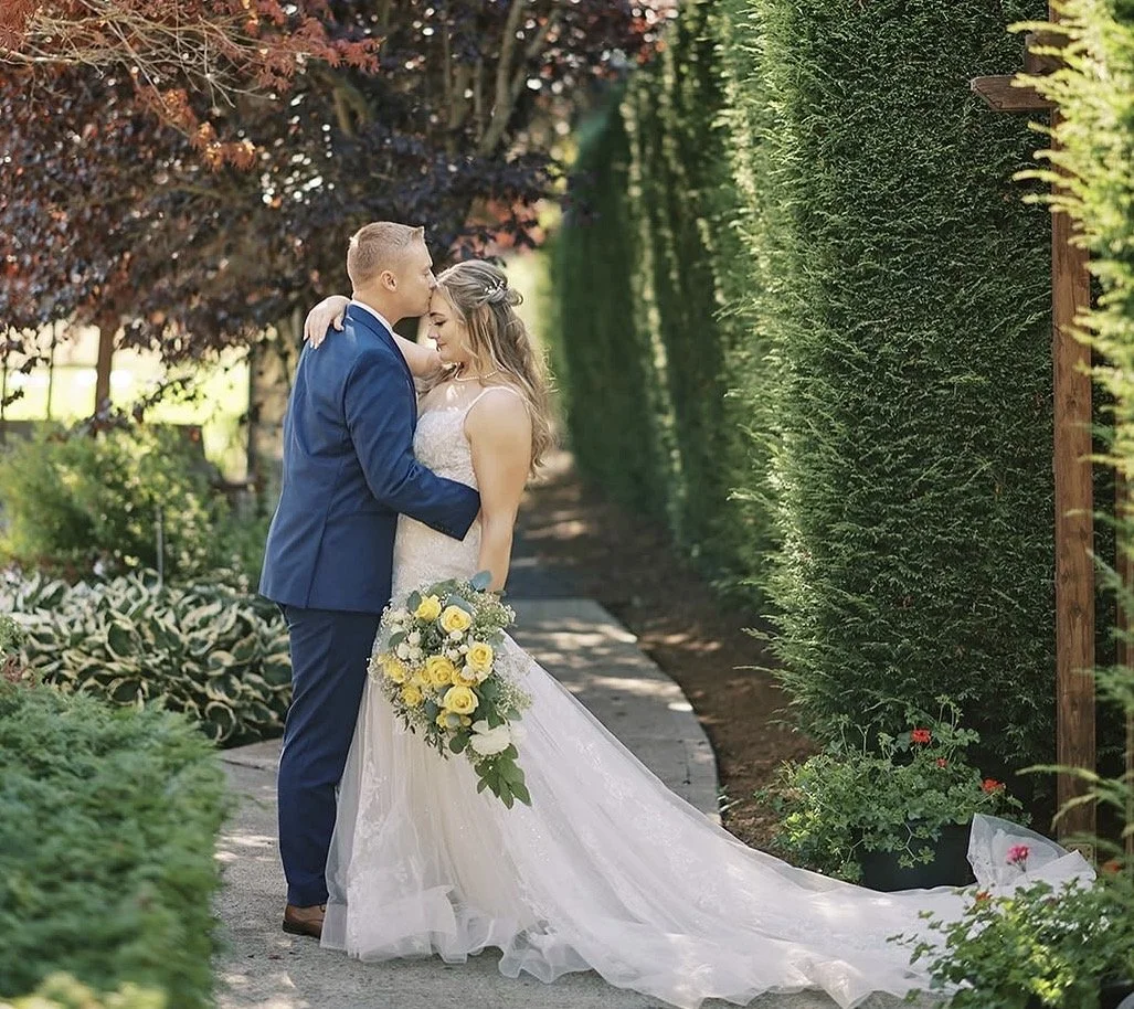 Newlywed couple in a garden with a cascading yellow and white bridal bouquet