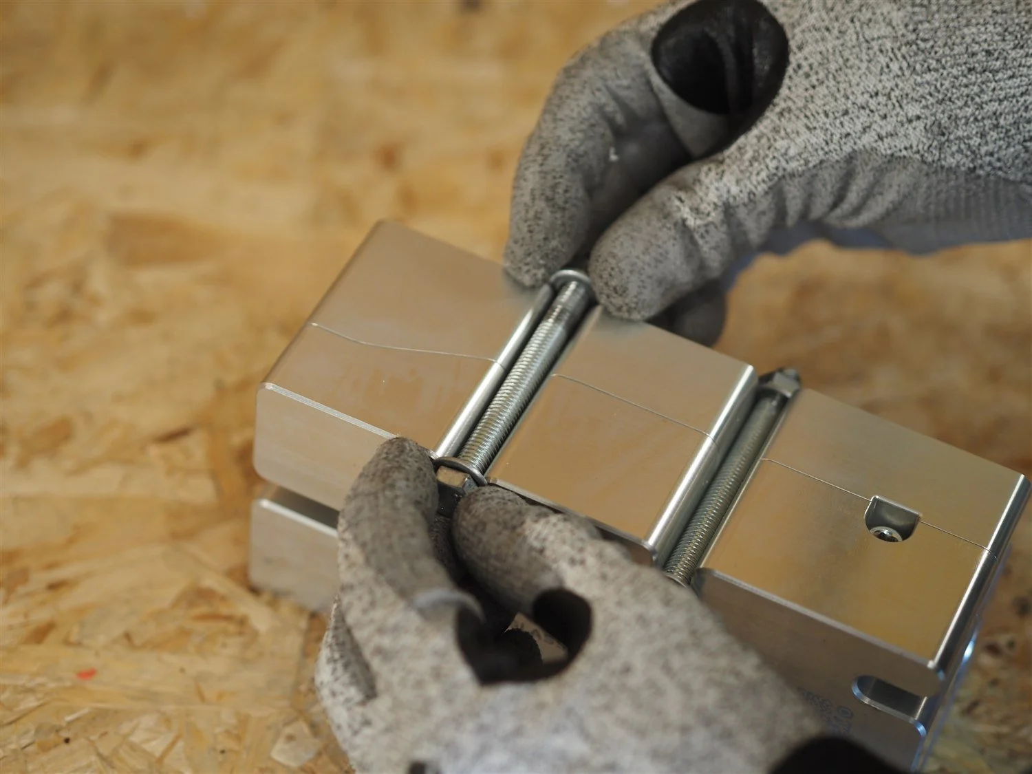 The arms mould closed with both locking bolts through it, being tightened by hand in a cut-resistant glove