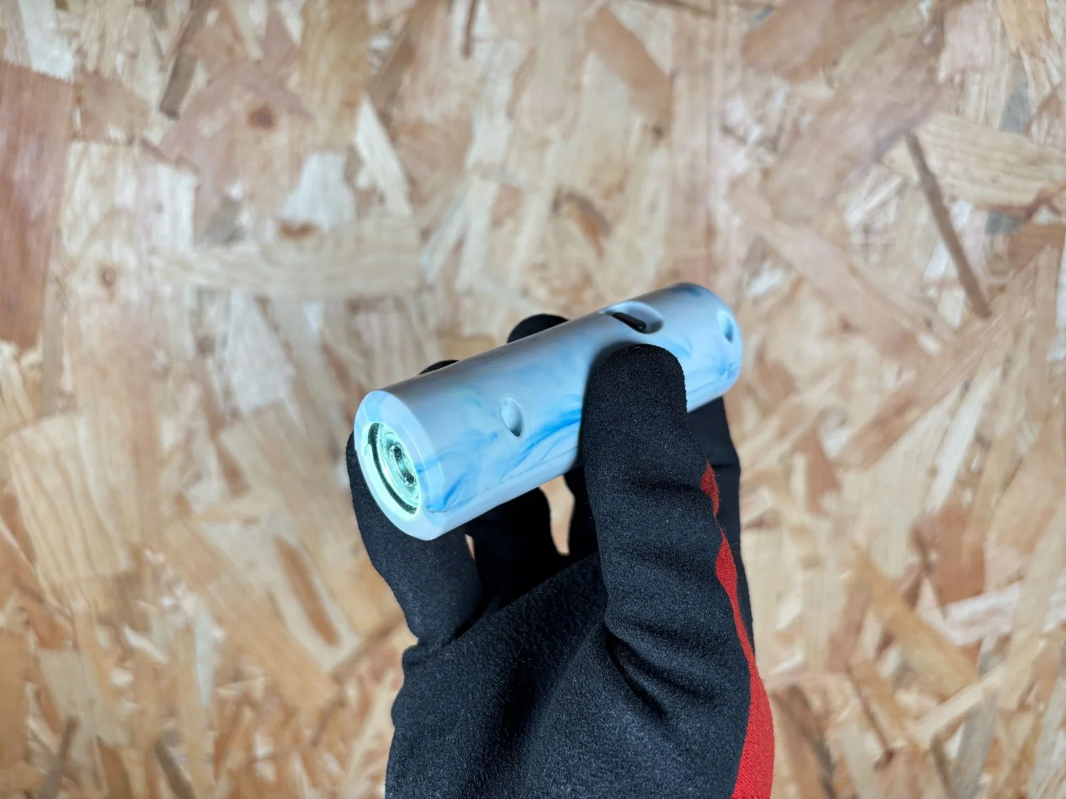 A finished recycled plastic torch with a black moulded body, standing upright on a workbench.