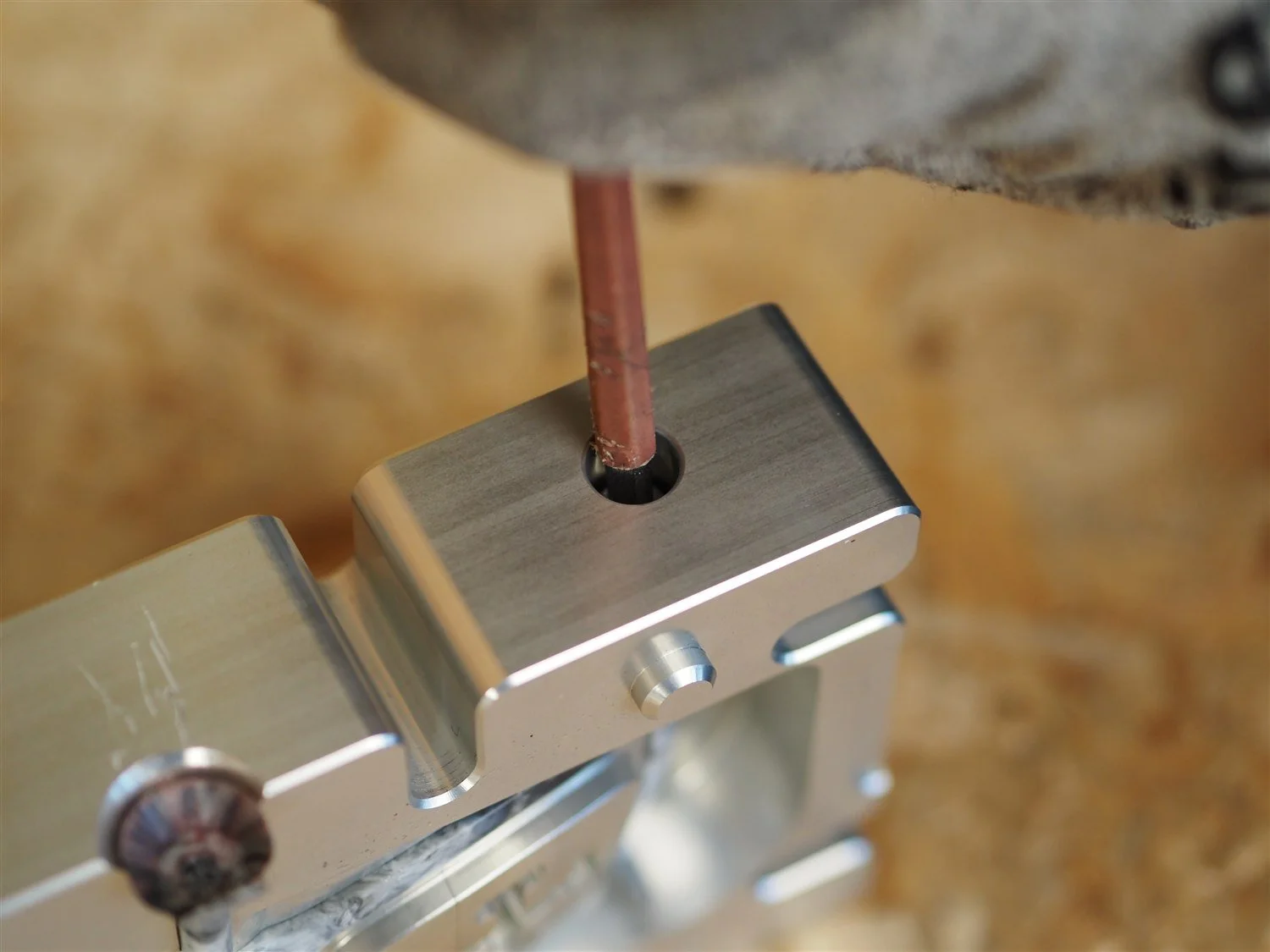 A locating pin being drawn out of the closed frame mould with a hand tool, before the mould is opened