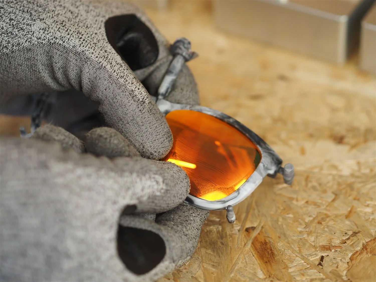 An orange mirrored lens being pressed into the frame, seated along the outer edge with the nose-piece end still to go