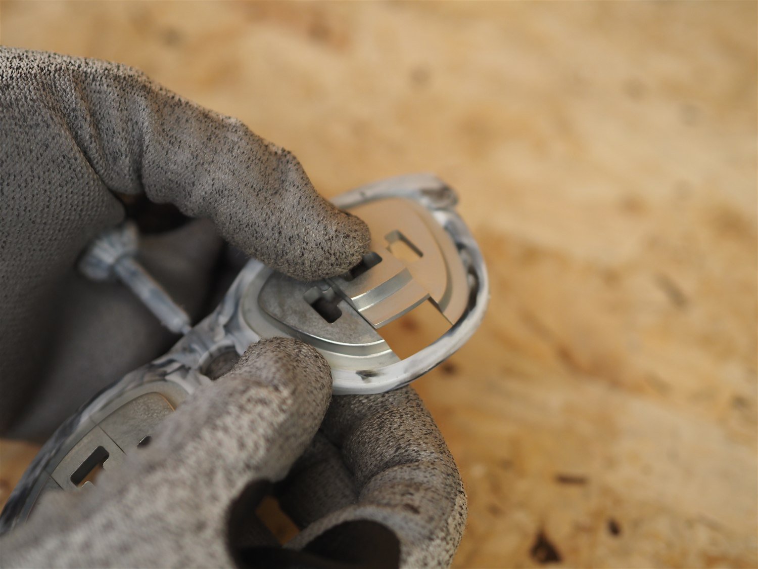A lens insert being worked out of one lens opening in the moulded frame, held in a gloved hand