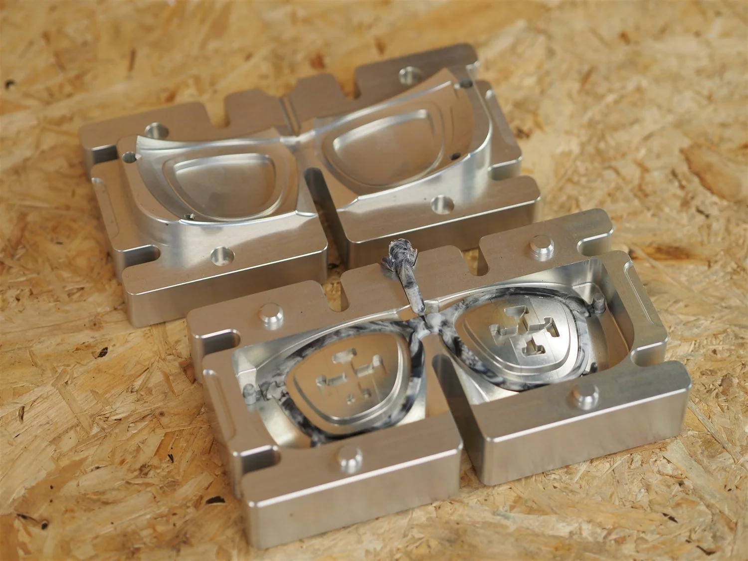 The frame mould opened into two halves, the moulded frame still sitting in the lower cavity with its sprue and runner attached