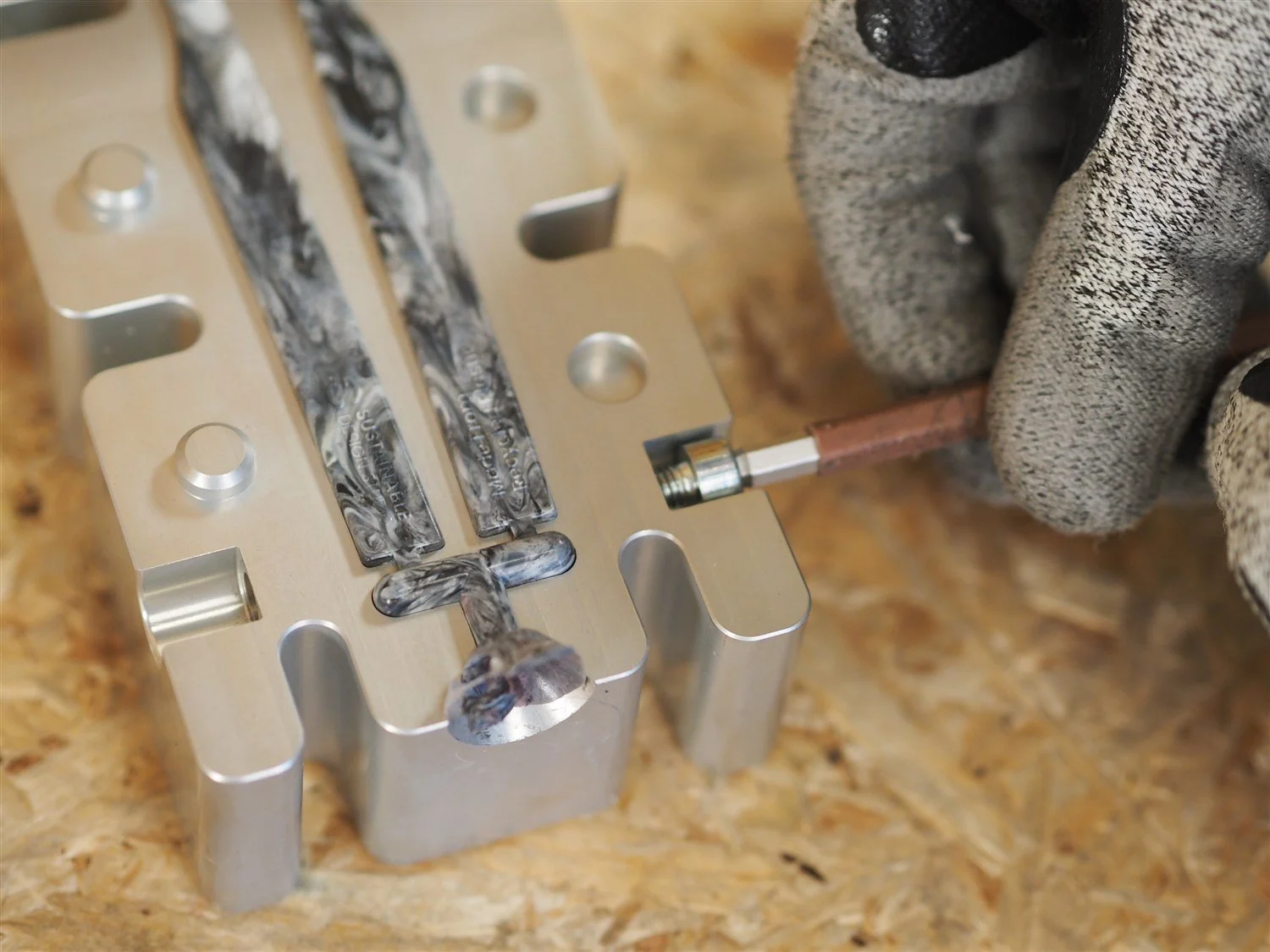 A locating pin being drawn out of the open arms mould with a hand tool, the moulded arms still lying in the cavity
