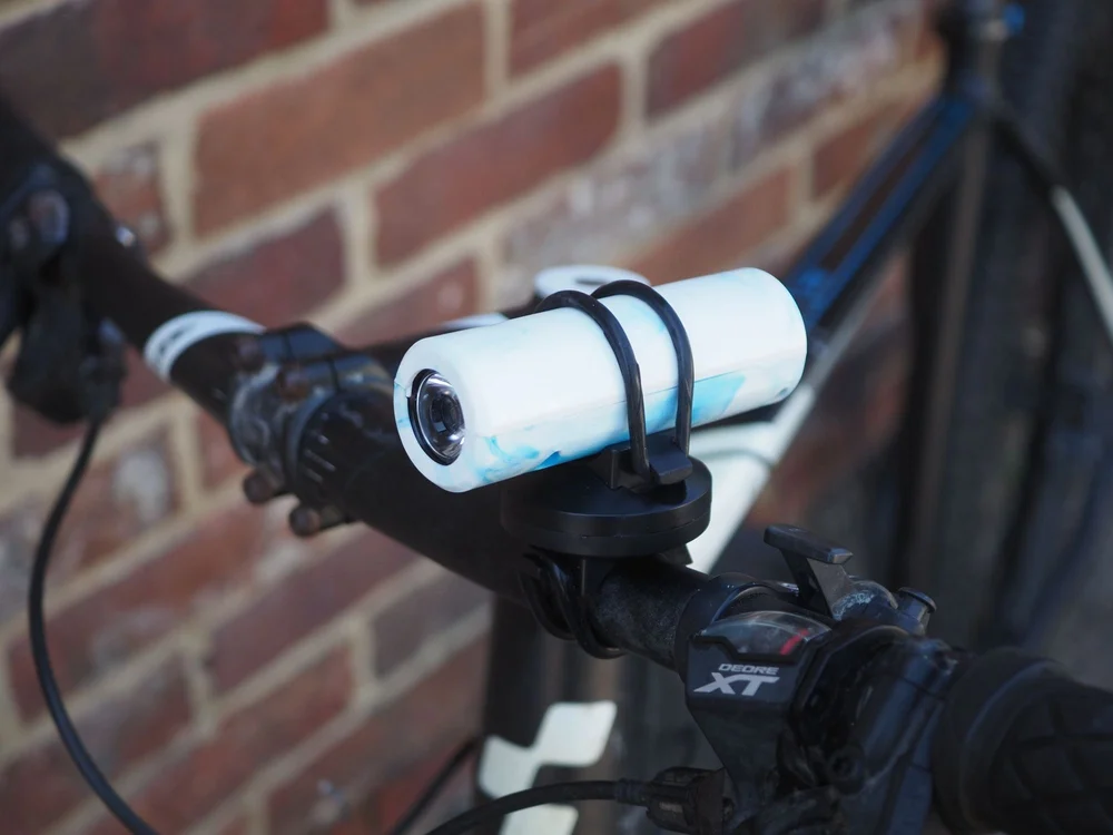 The finished recycled plastic torch mounted on a bicycle handlebar.