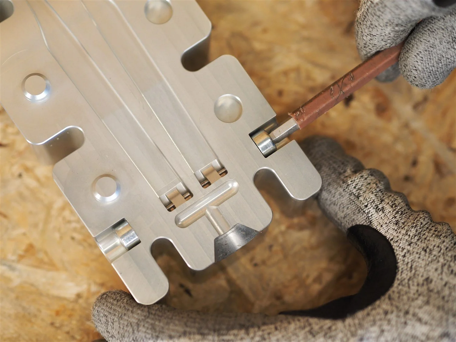 A locating insert being driven into its seat on the open face of the arms mould, with the two arm cavities and the T-shaped runner alongside