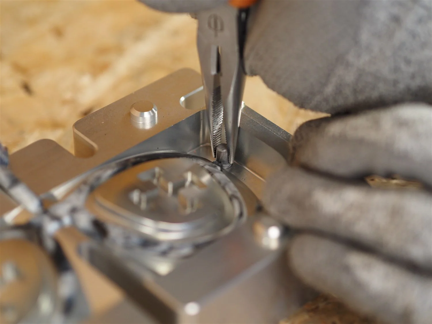 Pliers gripping one of the four pulling pins on the moulded frame, which is still seated in the lower half of the mould with its lens inserts in place