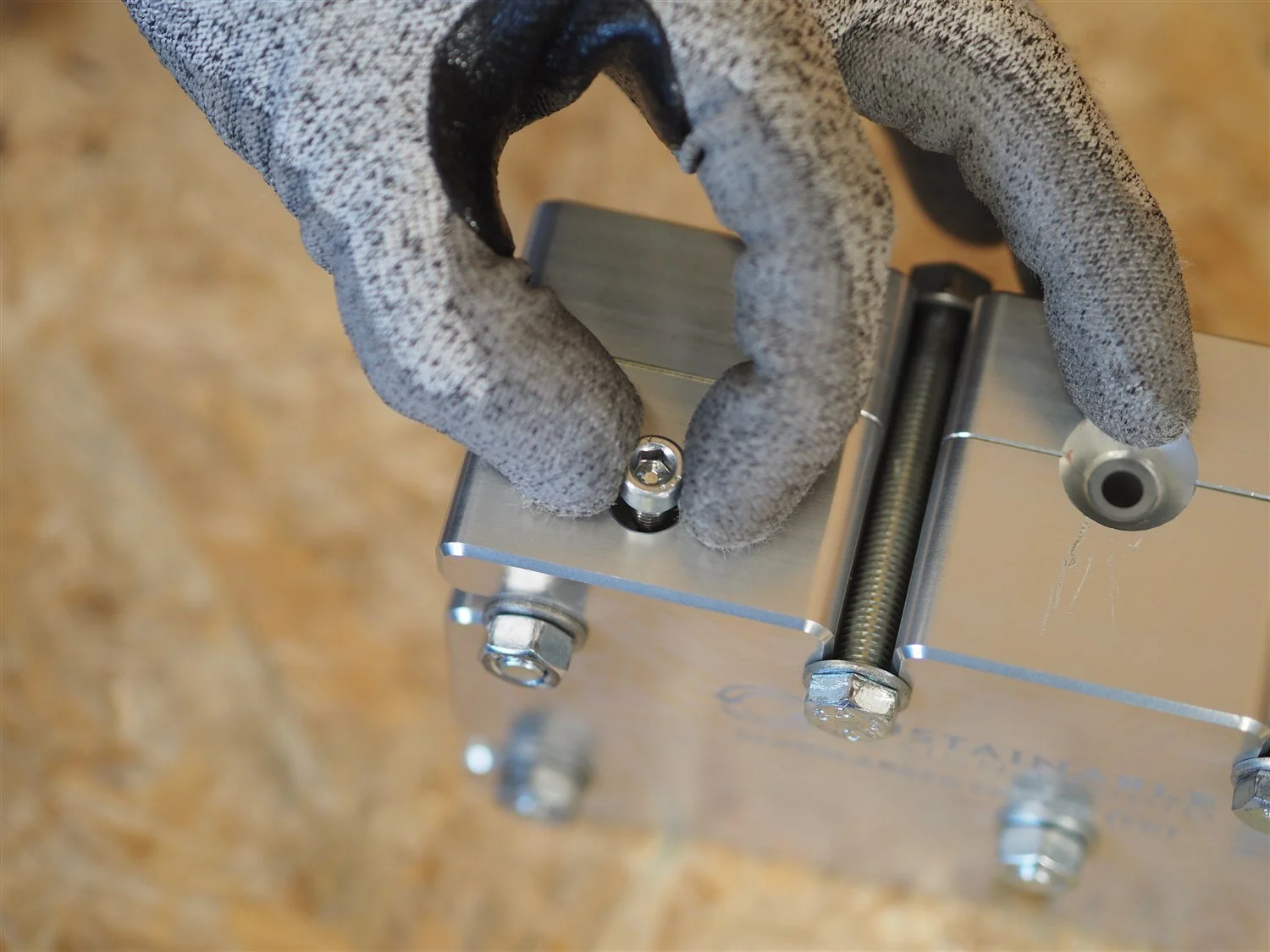 A gloved hand seating a locating pin into the frame mould, with one of the main locking bolts already through the block