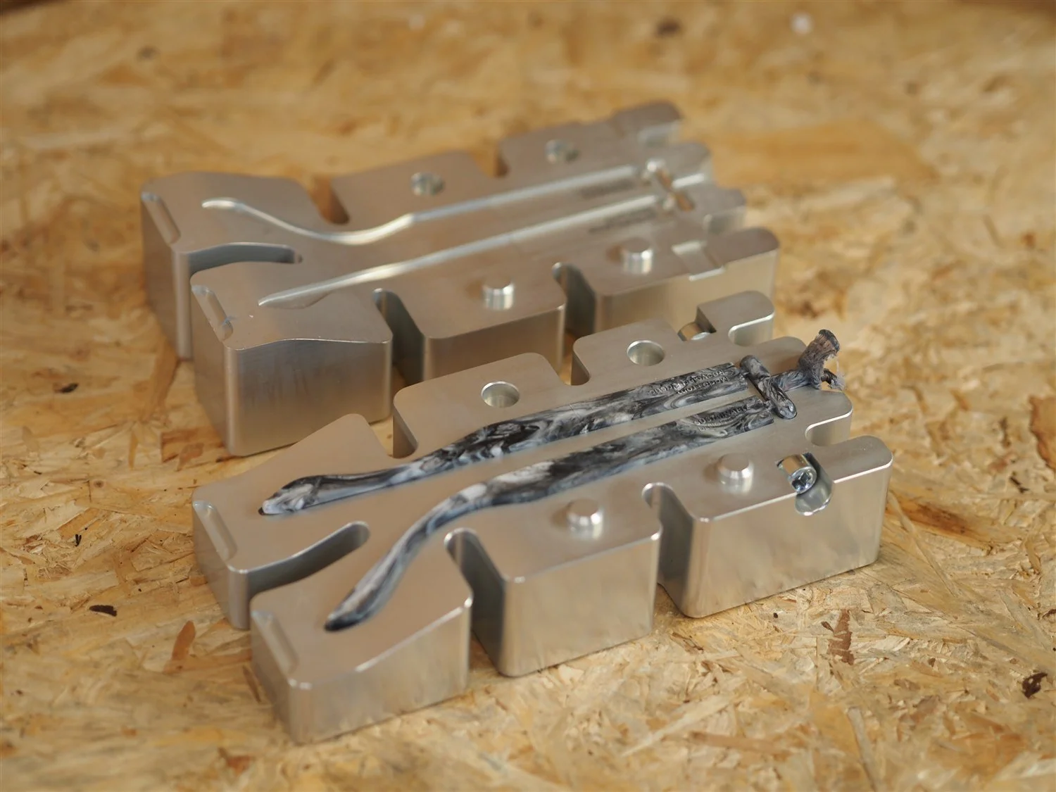 The arms mould opened into two halves, both moulded arms still lying in the lower cavity joined by the runner