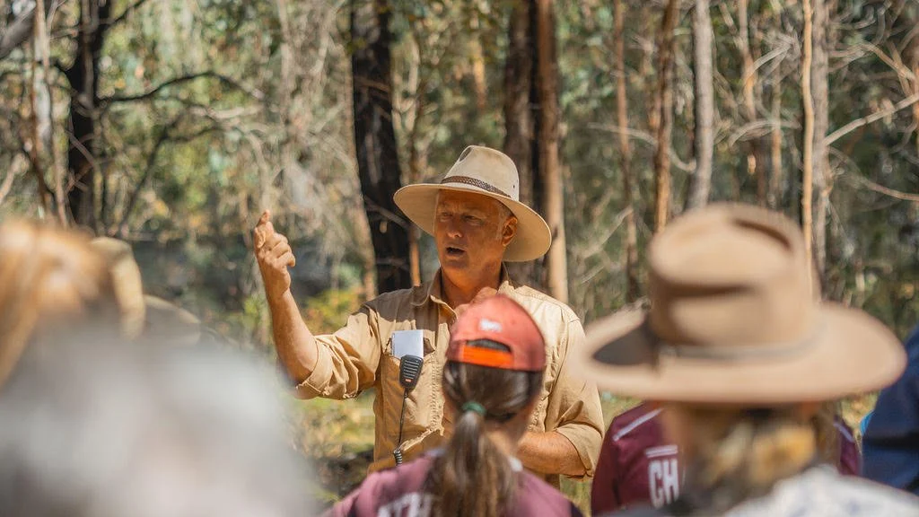 A Quoll HQ wildlife specialist speaking with a group of visitors in the bush during a guided tour