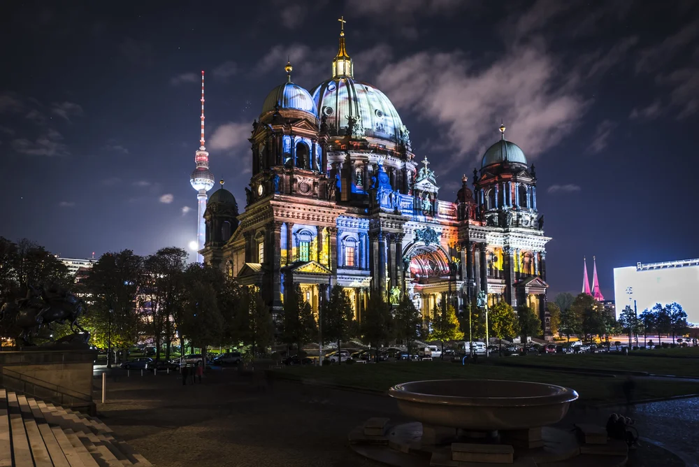 Berlin Cathedral illuminated in colourful projections, with the TV Tower behind it