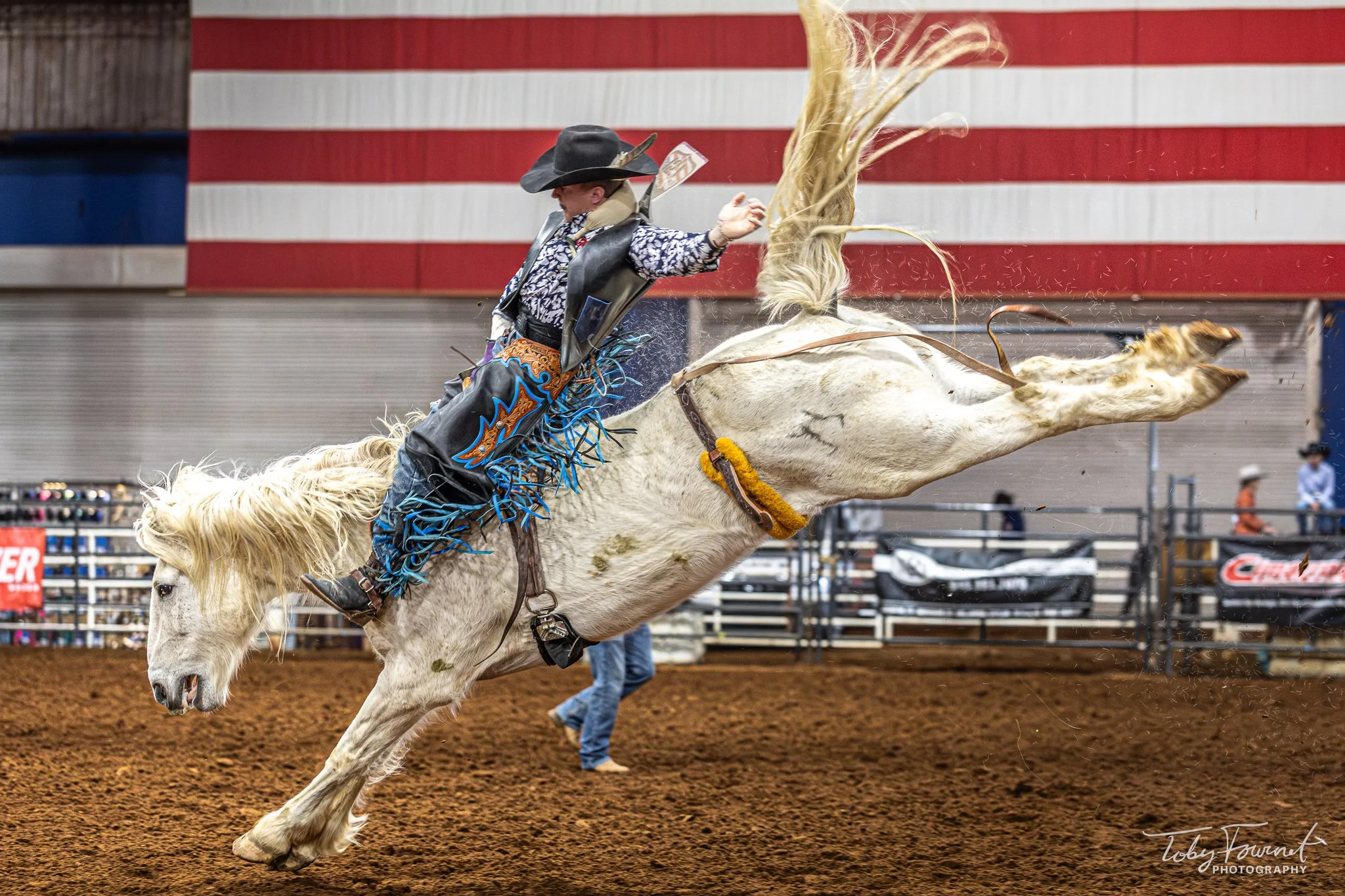 Rider on a white bucking horse in the arena
