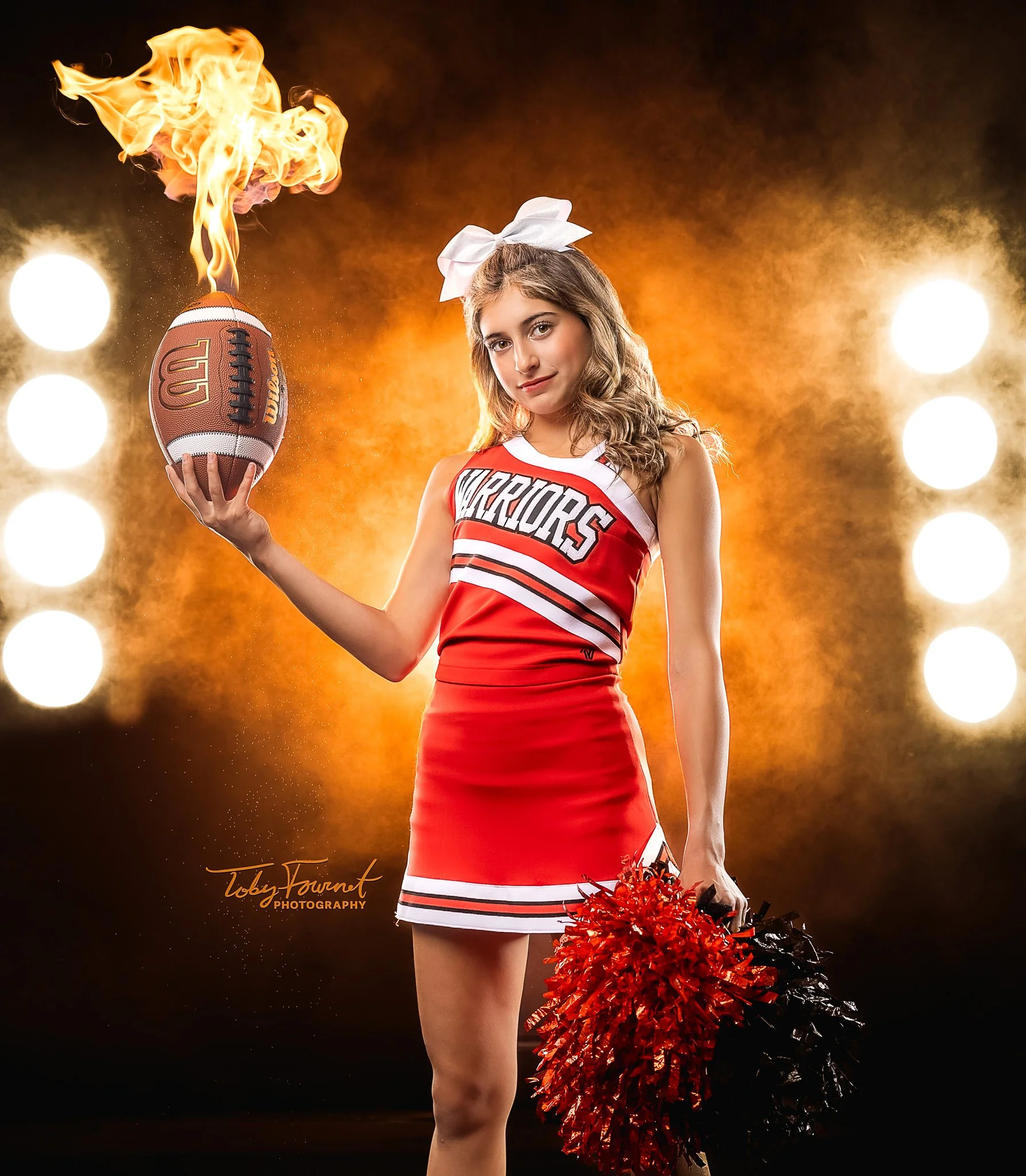 Cheerleader holding a football with a flame effect against golden lighting