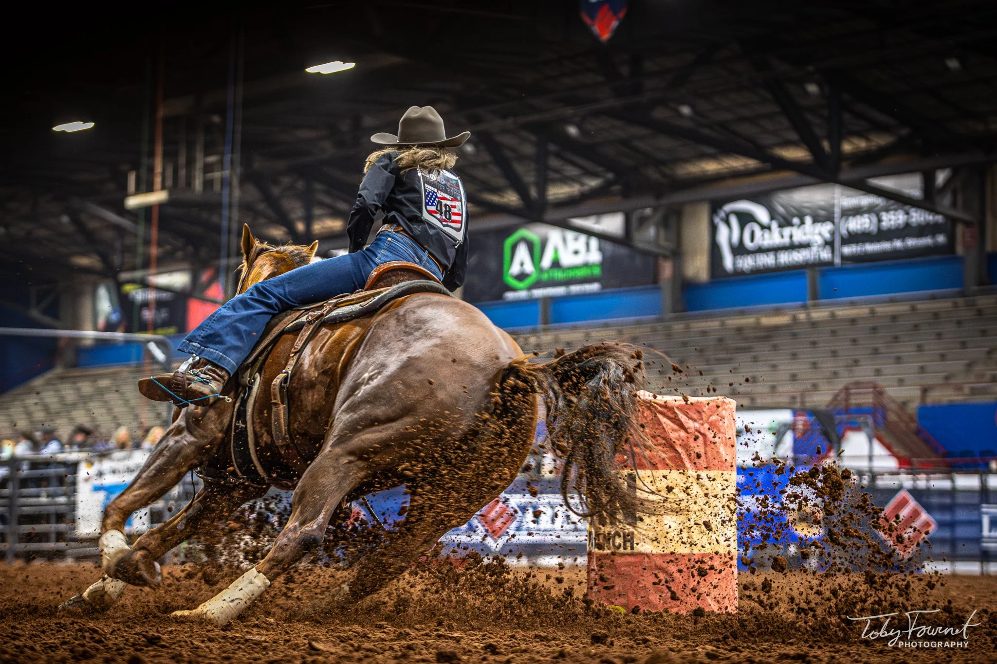 Barrel racer turning with dirt flying behind the horse