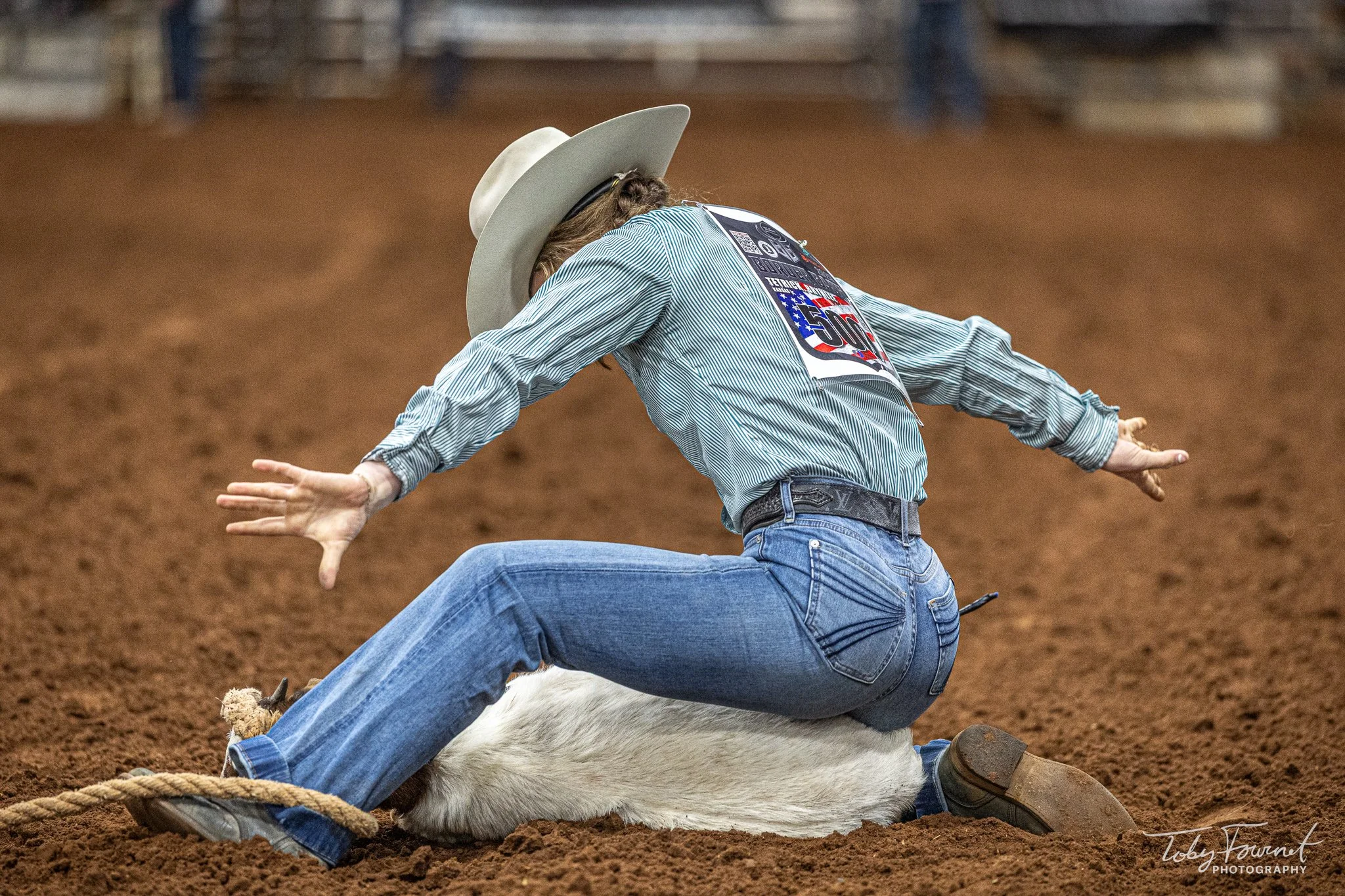 Rodeo competitor raising both hands after tying a goat