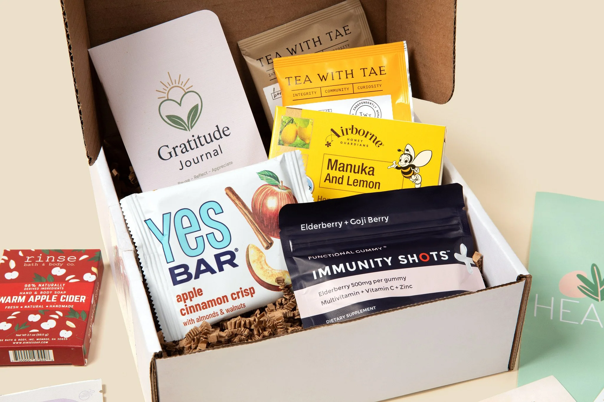 Open HealthBoxed employee wellness box with a gratitude journal, herbal tea, honey lemon drops, a snack bar and immunity gummies