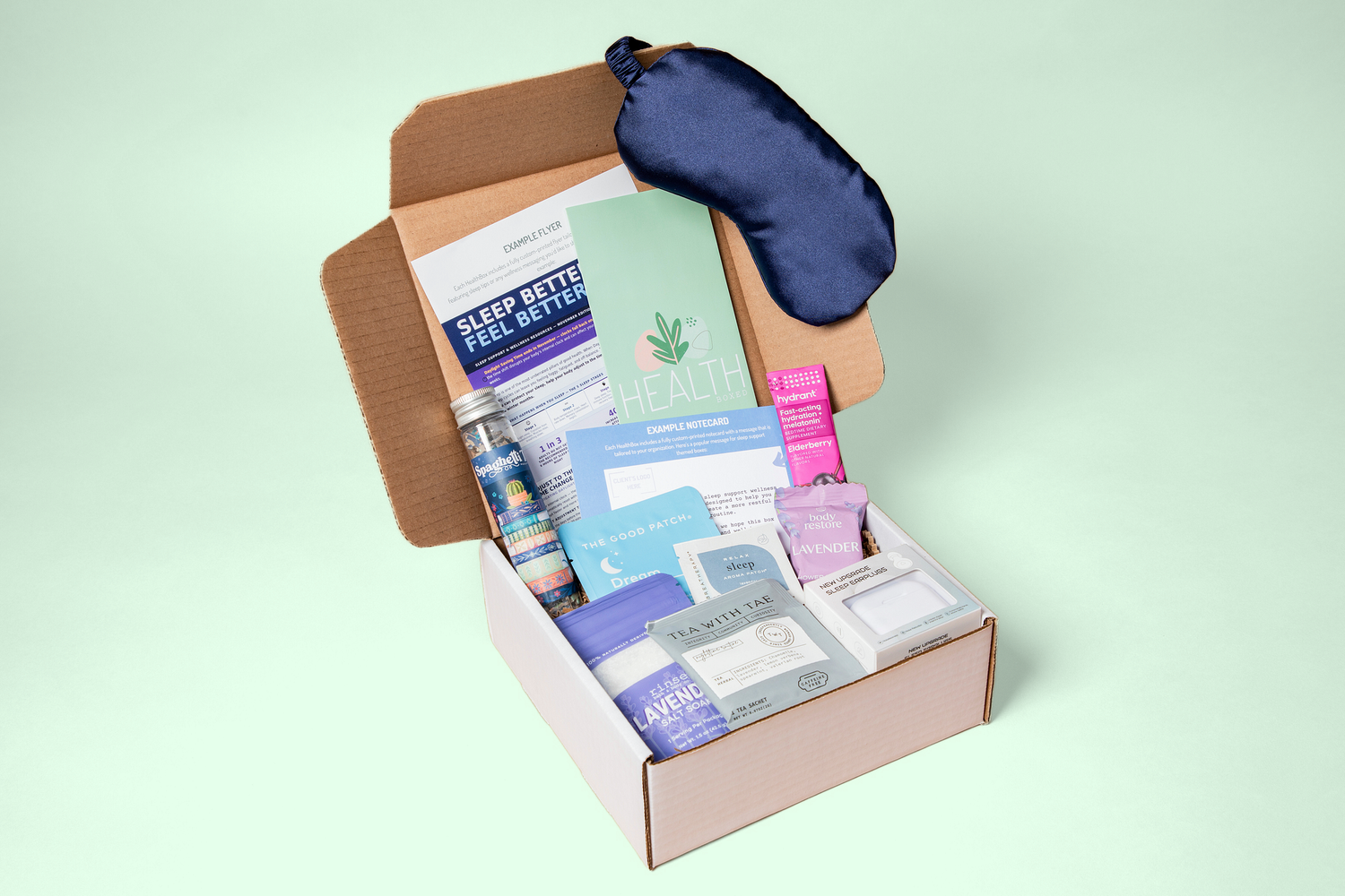 A sleep support HealthBoxed wellness box with a silk eye mask, lavender bath salts, tea and printed sleep tips