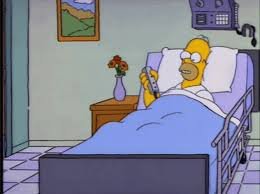 A man (Homer Simpson) sits in a hospital bed & plays with the up & down feature of the bed. 