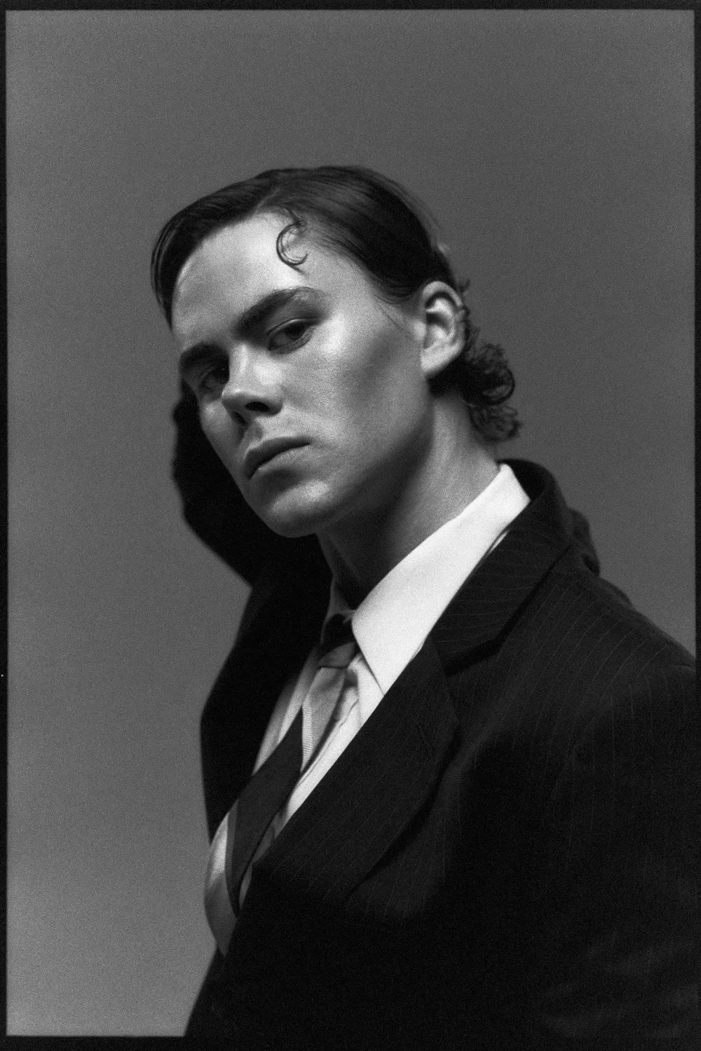 Portrait of the dancer, head tilted, slicked hair, suit and tie