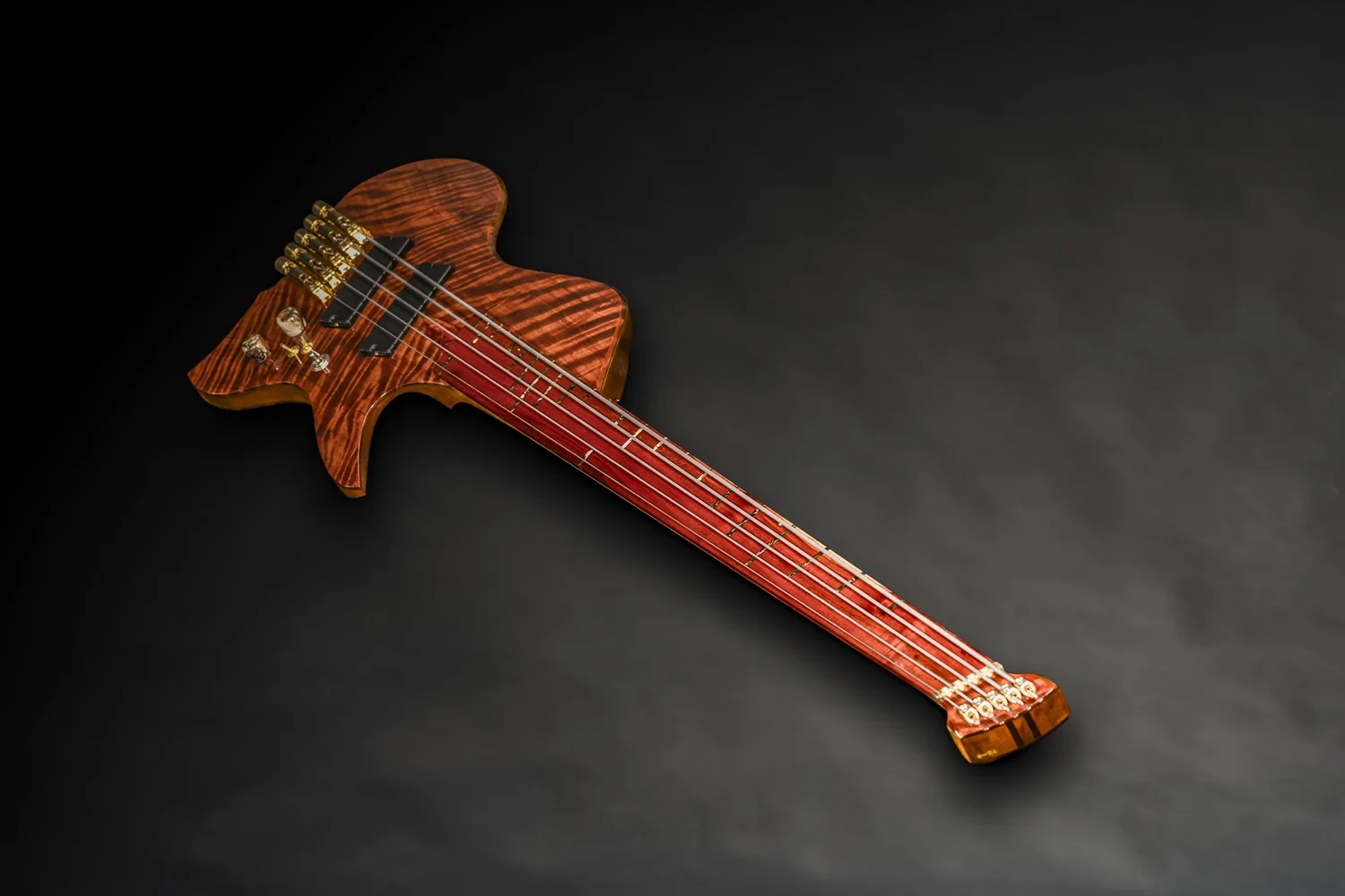 Full diagonal view of a headless Famine fretless five-string bass with a red fingerboard and gold hardware