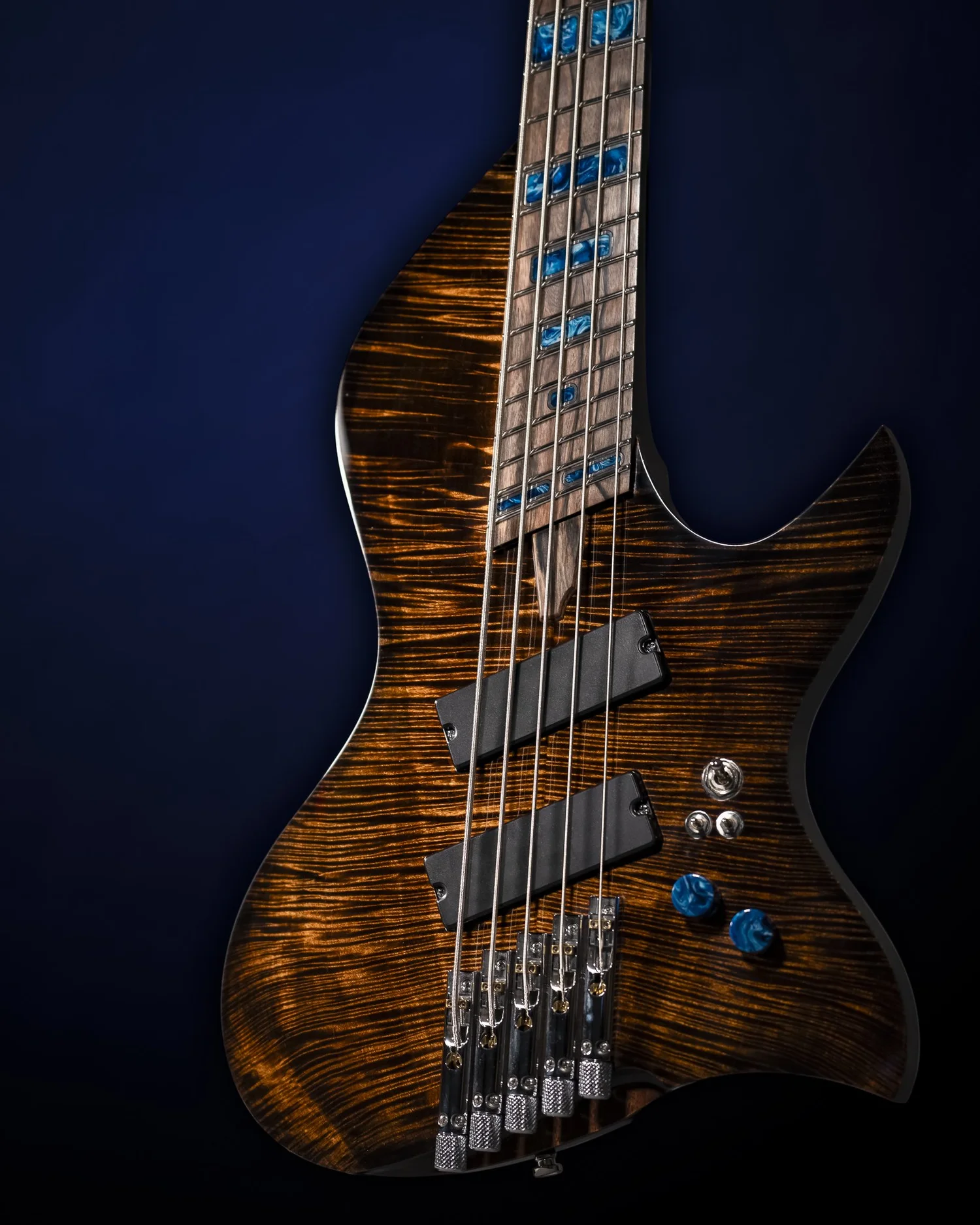 Brown figured Famine Bass with blue inlays and controls, viewed from the front at an angle