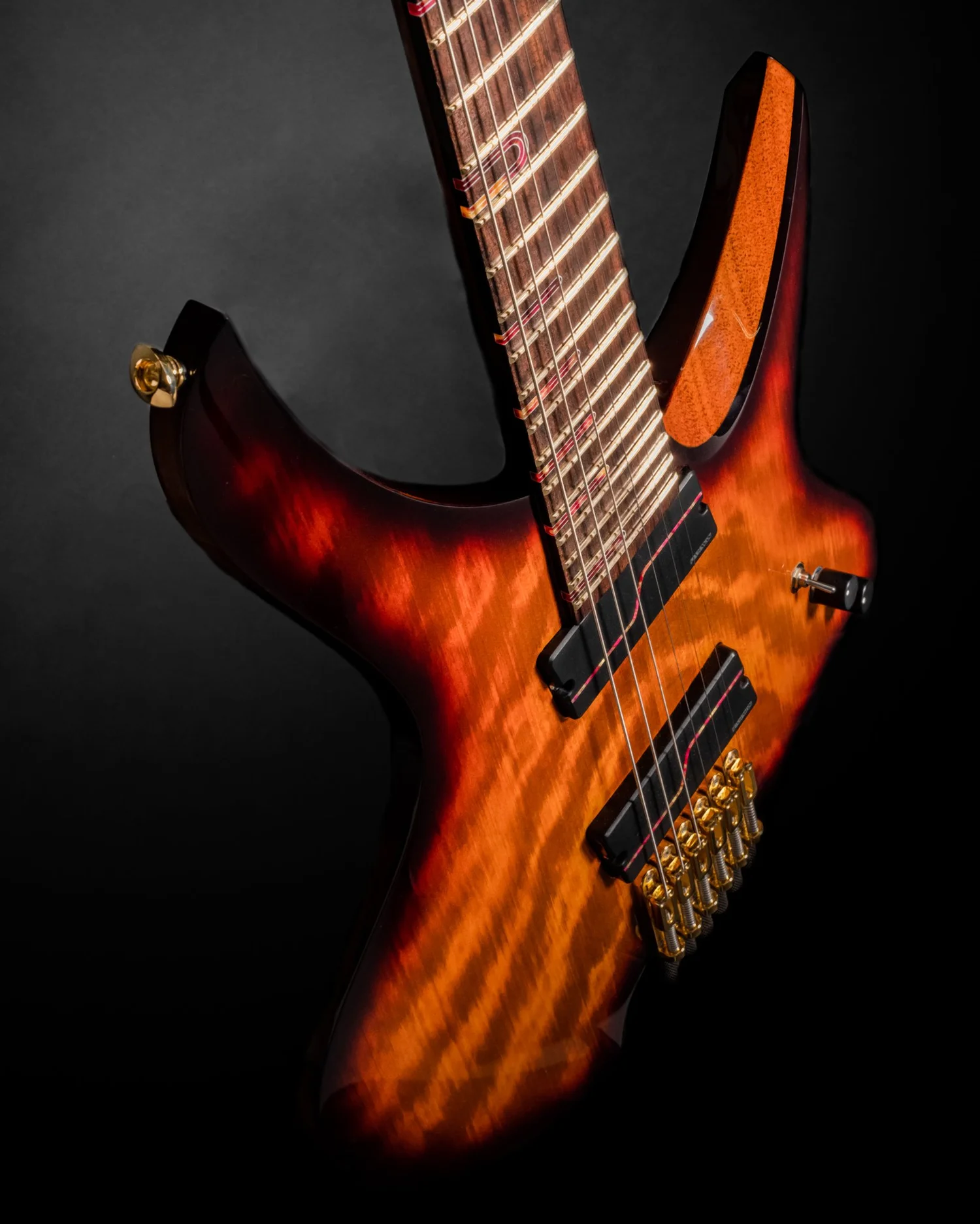 Angled front detail of a sunburst Famine Guitar showing its curved top and individual bridge units