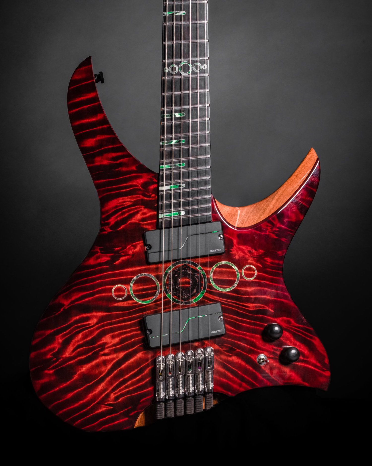 Front detail of a red Famine Guitar with circular body inlays and individual bridge units