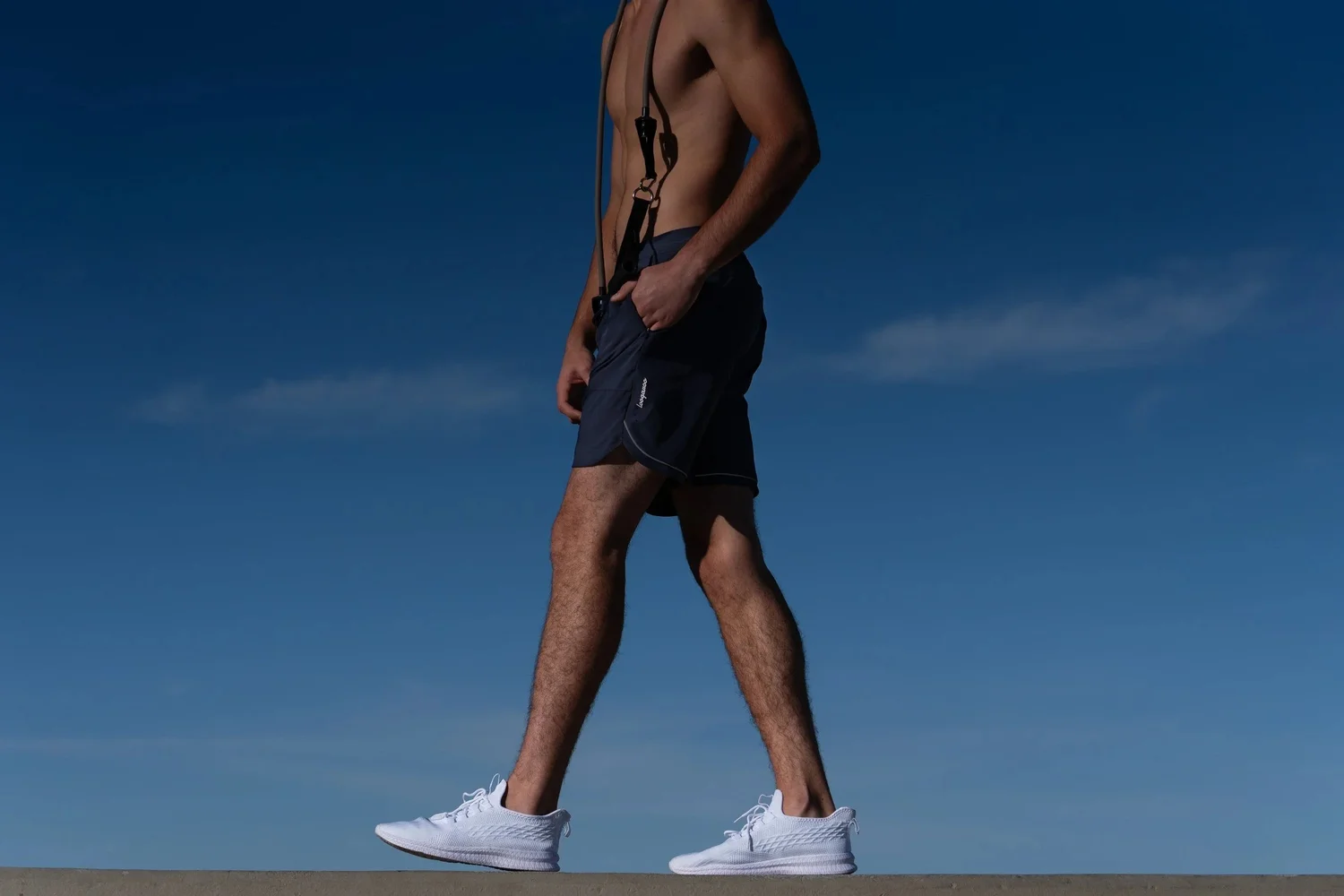 Loogaroo's new men's fitness and wellness apparel collection photographed on location in Los Angeles. Featuring navy performance shorts and white athletic shoes against a striking California blue sky, this commercial activewear campaign combines modern sportswear product photography with authentic outdoor lifestyle imagery.