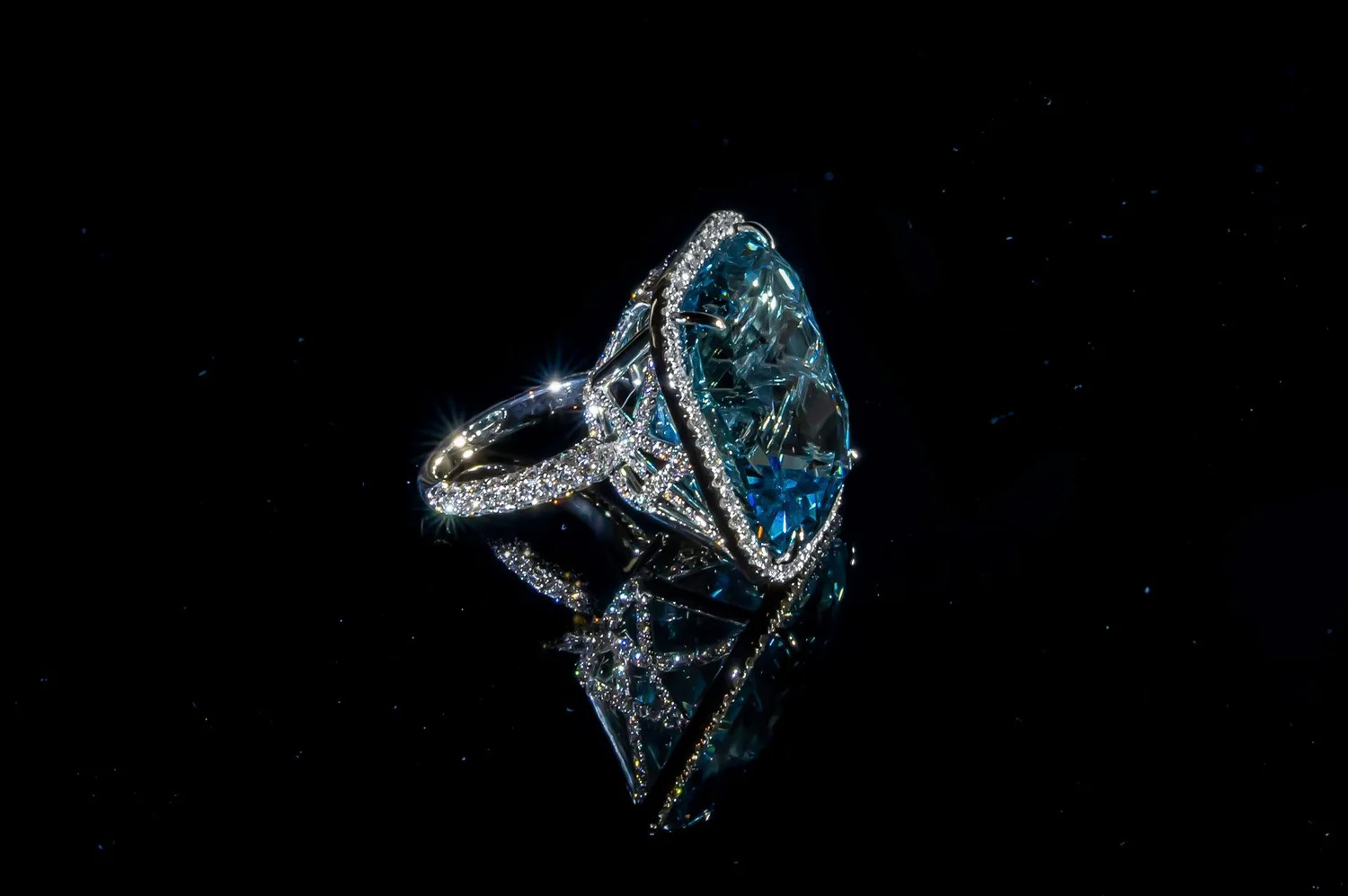 Luxury blue gemstone and diamond ring with sculpted highlights and a mirrored black reflection, photographed for a premium Black Friday jewelry campaign.