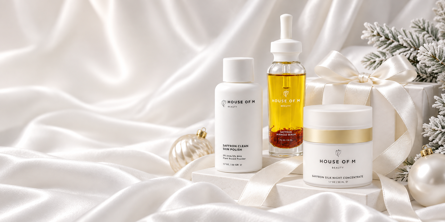 House of M skincare products styled on white satin with gift boxes, pearl ornaments and frosted pine for a luxury Christmas product photography campaign.