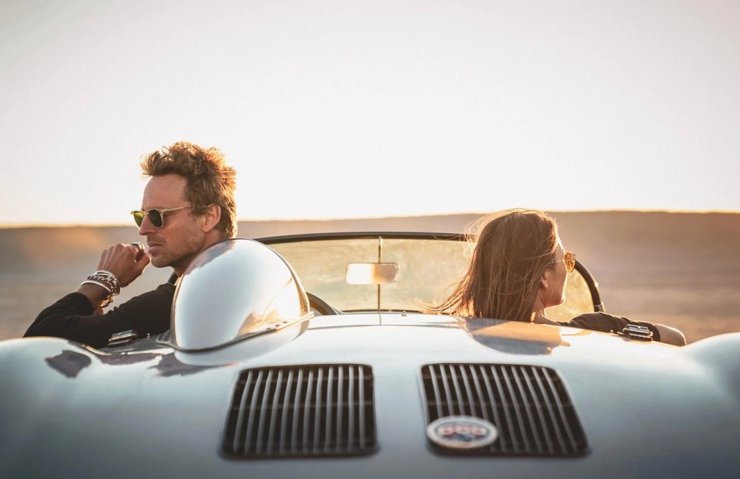 Models in a vintage convertible for a menswear and jewelry campaign at golden hour